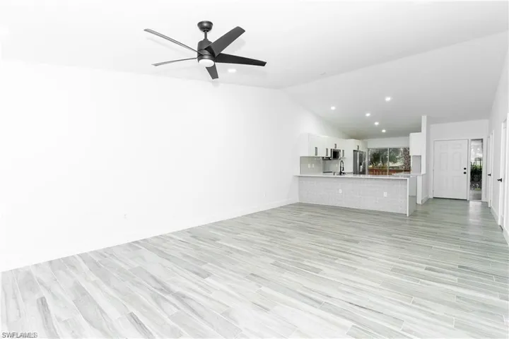 Unfurnished living room featuring vaulted ceiling, a ceiling fan, light wood-style flooring, and recessed lighting