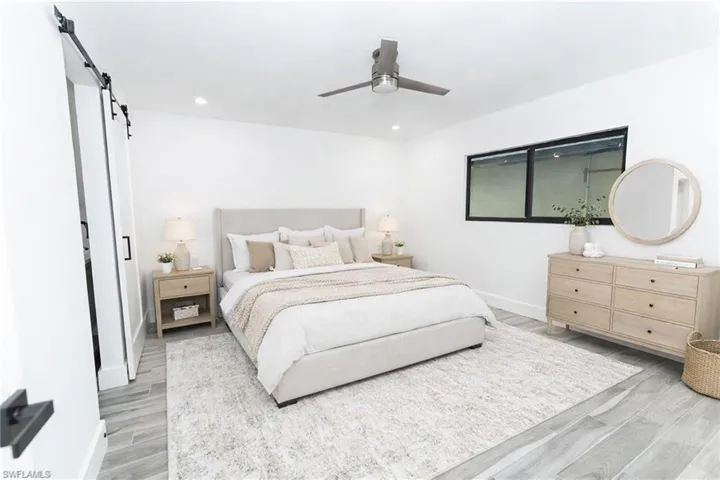 Bedroom with a barn door, light wood-style floors, a ceiling fan, and recessed lighting