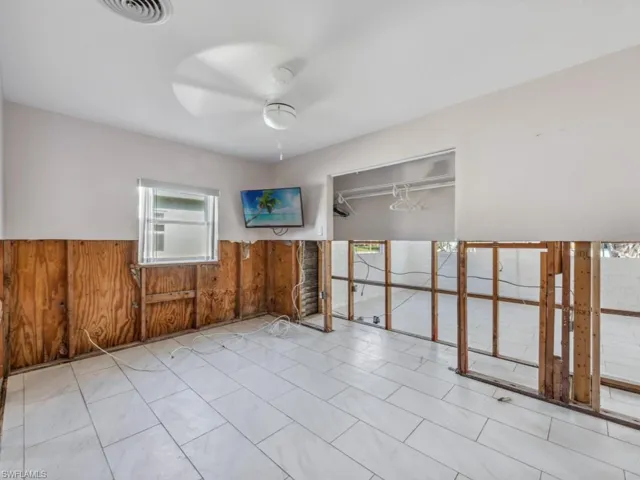Unfurnished room with wood walls, plenty of natural light, and ceiling fan
