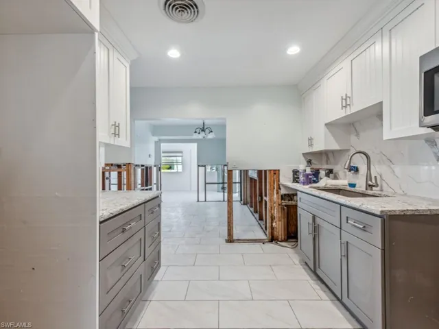 Kitchen with gray cabinets, white cabinetry, and sink