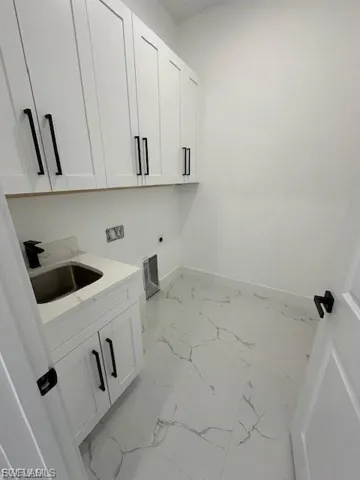 Laundry room featuring cabinet space, light marble finish flooring, and electric dryer hookup