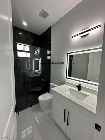 Full bath with a shower stall, vanity, and light marble finish floors