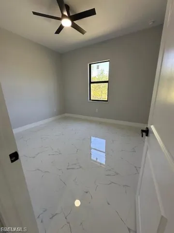 Unfurnished room with light marble finish flooring and ceiling fan