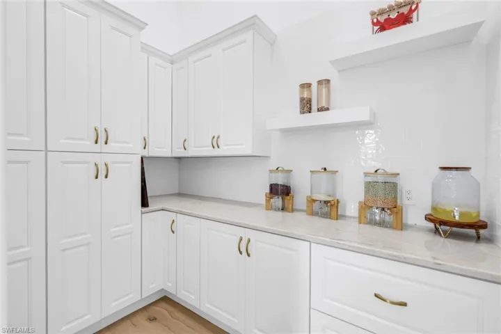 Bar with open shelves, white cabinetry, light stone counters, light wood finished floors, and decorative backsplash