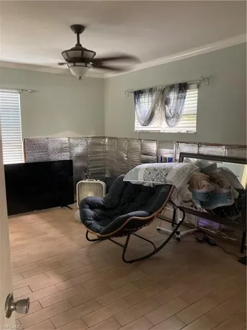 Bedroom featuring light wood-type flooring, ceiling fan, and crown molding