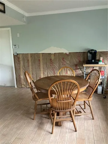 Dining space with light hardwood / wood-style floors and crown molding