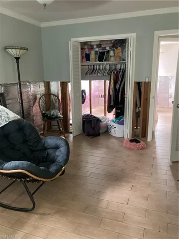 Bedroom featuring a closet, light wood-type flooring, and ornamental molding