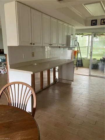 Kitchen with light hardwood / wood-style flooring, decorative backsplash, crown molding, and white cabinets