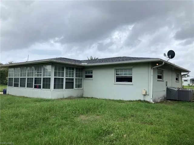 View of side of property featuring a lawn, a sunroom, and cooling unit