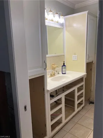 Bathroom featuring sink, tile patterned floors, and ornamental molding