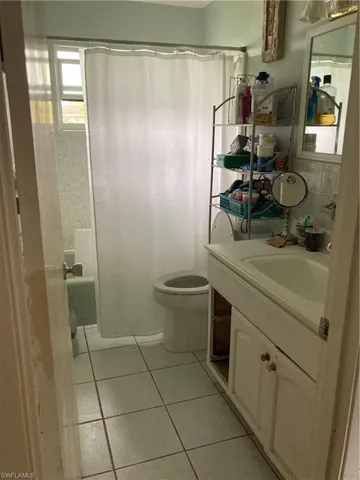Full bathroom with shower / bath combo, tile patterned flooring, vanity, and toilet