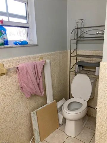 Bathroom featuring tile patterned flooring, toilet, and tile walls