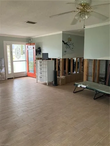 Unfurnished living room featuring a textured ceiling, crown molding, ceiling fan, and light hardwood / wood-style flooring