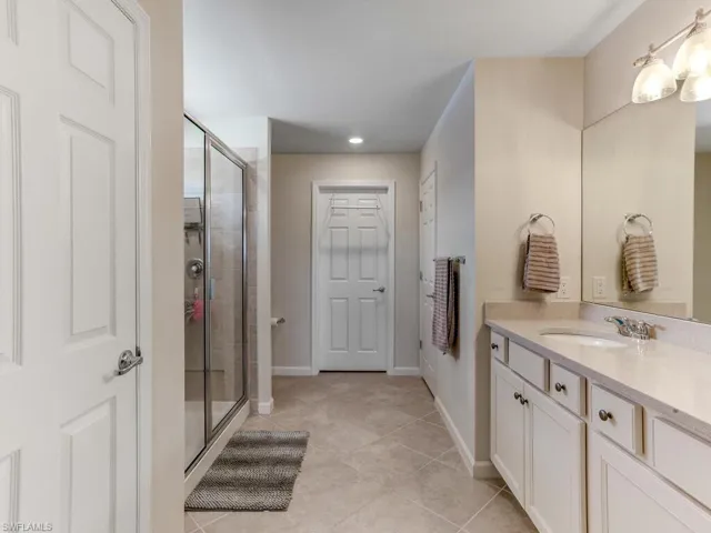 Bathroom featuring vanity, tile patterned flooring, and a shower with door