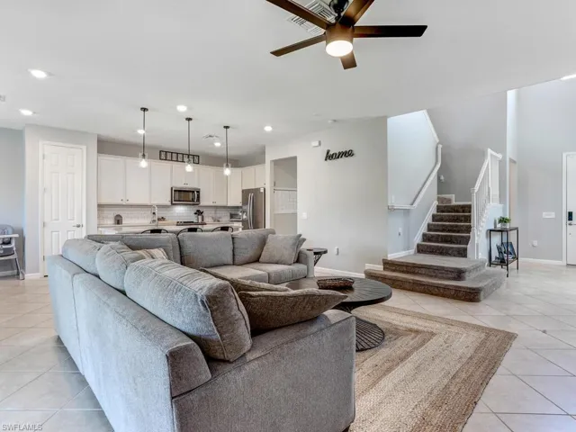 Living room featuring light tile patterned floors, sink, and ceiling fan
