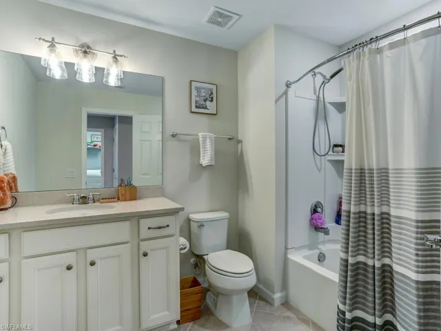 Full bathroom with vanity, toilet, shower / bath combo with shower curtain, and tile patterned floors