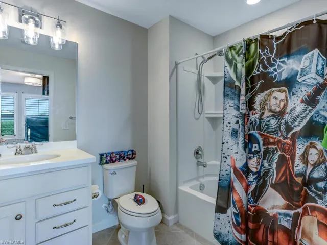 Full bathroom featuring shower / bath combination with curtain, tile patterned floors, vanity, and toilet