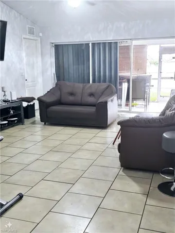 Tiled living room featuring vaulted ceiling