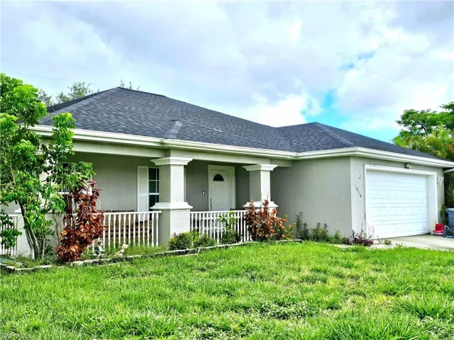 View of front of property featuring a porch, a garage, and a front lawn