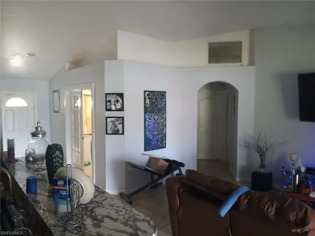 Tiled living room featuring vaulted ceiling