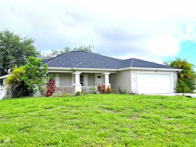 Ranch-style home with covered porch, a garage, and a front lawn