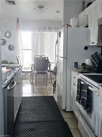 Kitchen featuring white range oven, white cabinetry, and light tile floors