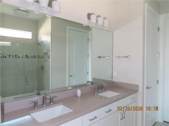 Full bathroom featuring double vanity and a shower stall