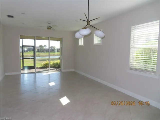 Unfurnished room featuring light tile patterned flooring, a water view, and a ceiling fan