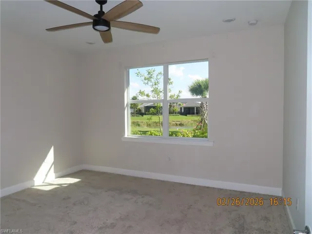 Carpeted spare room featuring baseboards and ceiling fan