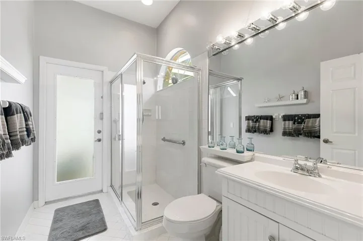 Bathroom with tile patterned floors, vanity, toilet, and an enclosed shower