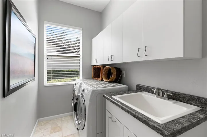 Laundry room featuring washer and clothes dryer, plenty of natural light, cabinets, and sink