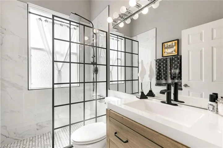 Bathroom featuring tiled shower, vanity, and toilet