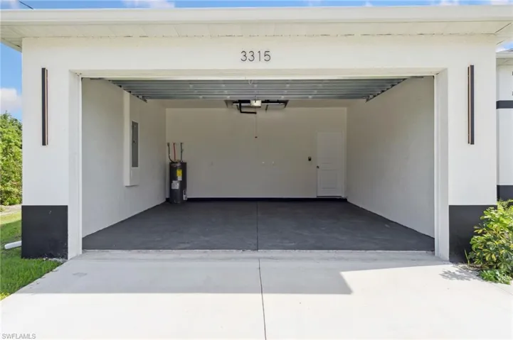 Garage featuring concrete driveway and electric water heater