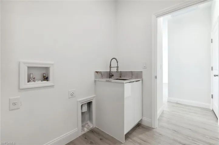 Clothes washing area with light wood finished floors, washer hookup, a sink, laundry area, and electric dryer hookup