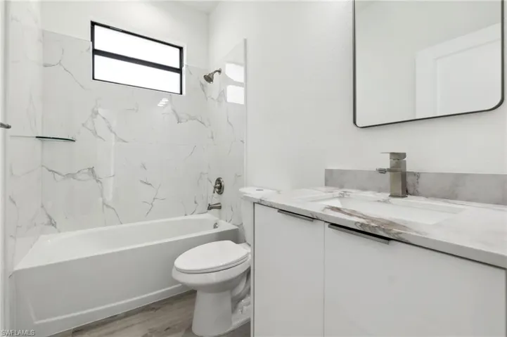 Bathroom featuring vanity, toilet, shower / tub combination, and wood finished floors