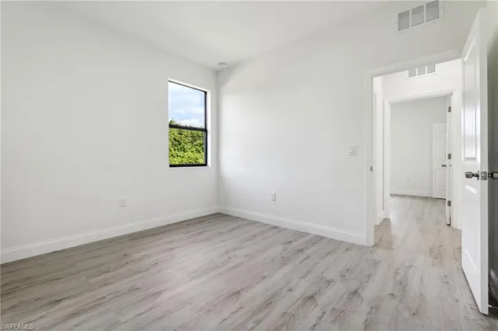 Empty room featuring baseboards, light wood-style floors, and visible vents