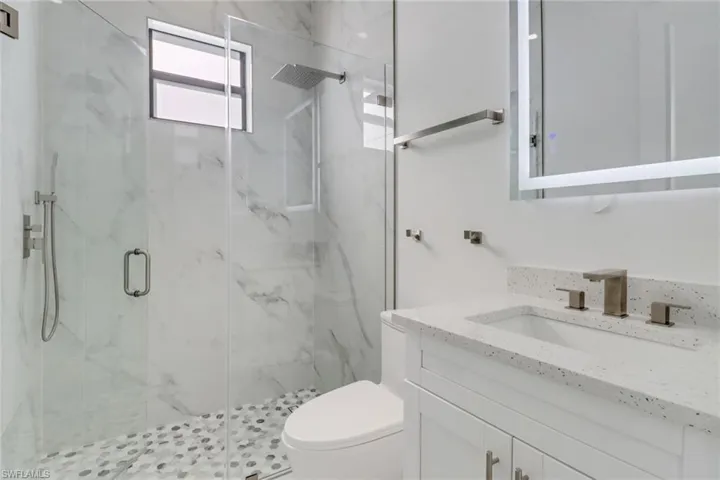 Full bath featuring vanity, a marble finish shower, and toilet