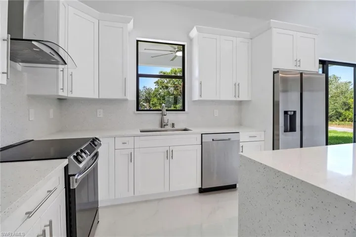 Kitchen with a ceiling fan, exhaust hood, a wealth of natural light, stainless steel appliances, and a sink