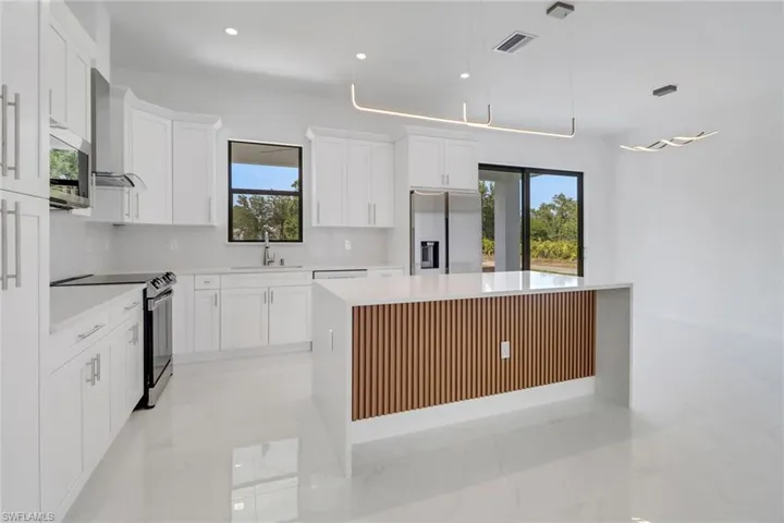 Kitchen featuring white cabinets, a kitchen island, light countertops, and appliances with stainless steel finishes