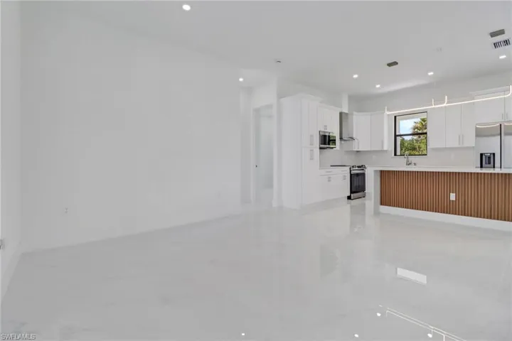 Kitchen with white cabinets, a sink, light countertops, stainless steel appliances, and open floor plan