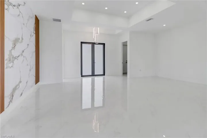 Spare room featuring a raised ceiling, marble finish floor, visible vents, and recessed lighting