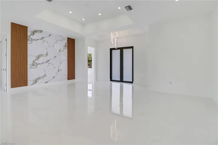 Empty room with visible vents, an accent wall, a tray ceiling, recessed lighting, and marble finish floor