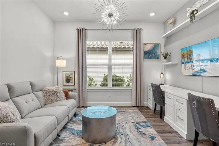 Den featuring floating shelves and chandelier