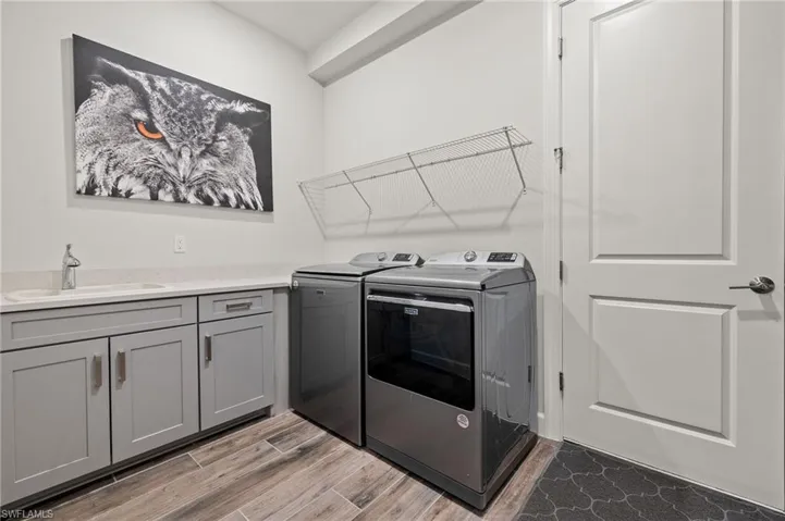 Laundry area featuring cabinets, washer and dryer, sink and nook with floating shelves