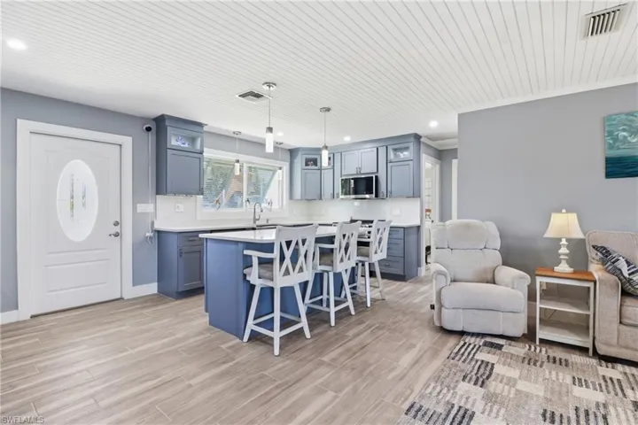 Kitchen with a breakfast bar area, decorative light fixtures, a kitchen island, tile floors, and blue cabinets.