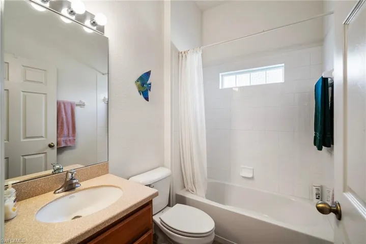 Full bathroom with toilet, shower / bathtub combination with curtain, and vanity