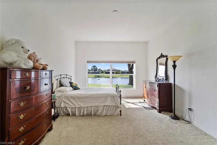 Bedroom with light colored carpet and a water view