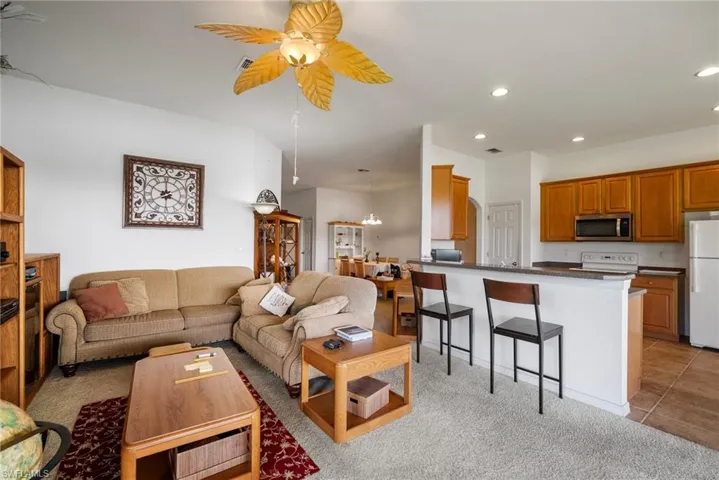 Living room with ceiling fan and light carpet