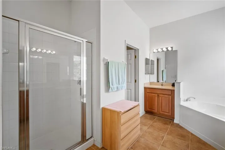 Bathroom featuring tile patterned flooring, shower with separate bathtub, and vanity
