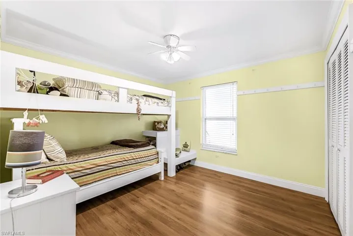 Bedroom featuring wood-type flooring, ornamental molding, a closet, and ceiling fan